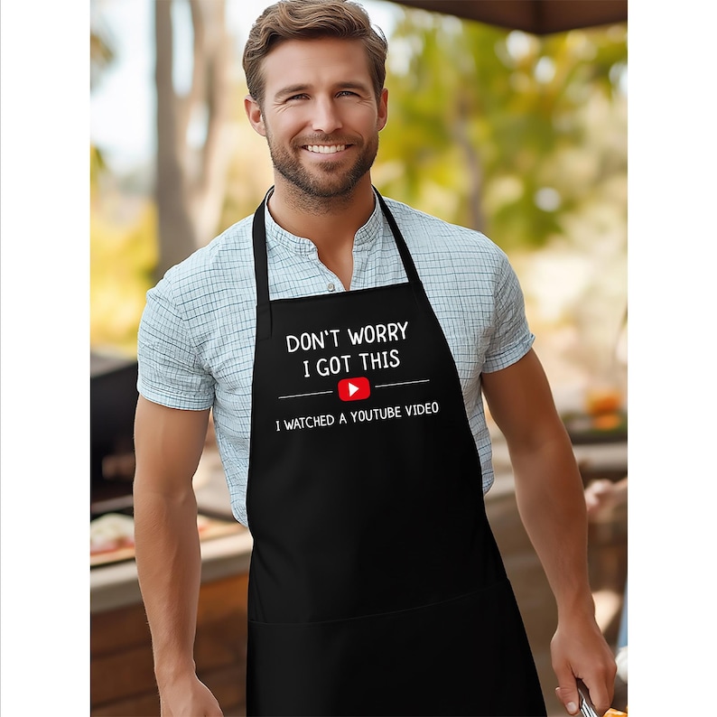 May include: Black apron with the text "DON'T WORRY I GOT THIS" above a YouTube logo and the text "I WATCHED A YOUTUBE VIDEO". The apron has a neck strap and waist ties.