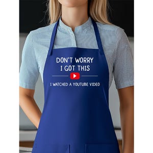 May include: A navy blue apron with the text "DON'T WORRY I GOT THIS" above a YouTube play button logo and the text "I WATCHED A YOUTUBE VIDEO". The apron has a bib and neck strap.