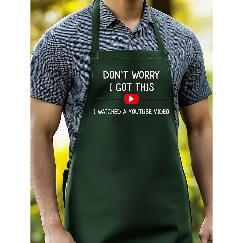 May include: A dark green apron with white text that reads "DON'T WORRY I GOT THIS" above a YouTube play button and the text "I WATCHED A YOUTUBE VIDEO". The apron has a neck strap and waist ties.