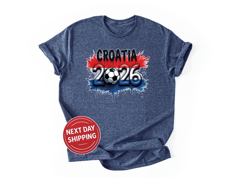 Puede incluir: Camiseta azul marino con un dise&ntilde;o gr&aacute;fico. El dise&ntilde;o incluye la palabra "CROATIA" en negro, el n&uacute;mero "2026" en blanco y un bal&oacute;n de f&uacute;tbol. El dise&ntilde;o incorpora los colores rojo, blanco y azul, con un efecto de pintura goteando.