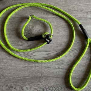 May include: Bright neon green dog lead with a loop handle and a metal ring. The lead has a black connector and is made of a durable, woven material. The lead is designed for pet owners.