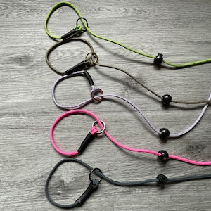 May include: Five different coloured dog collars with black metal clasps and black beads. The collars are made of rope and are in the colours green, purple, pink, and grey.