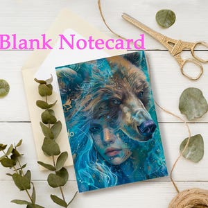 May include: A blank notecard with an artistic illustration of a woman's face merging with a bear's head, in shades of blue, brown, and gold. The words "Blank Notecard" are in pink. The card is placed in an envelope with decorative elements.