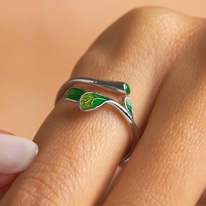 May include: A silver ring with a green enamel leaf design. The ring is adjustable and can be worn on any finger.