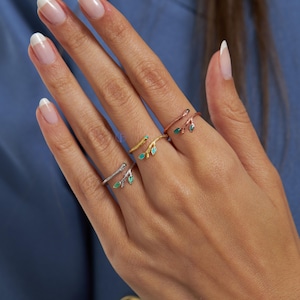 May include: Three gold, silver, and rose gold rings with a twig design and green enamel leaves. The rings are adjustable and can be worn on any finger.