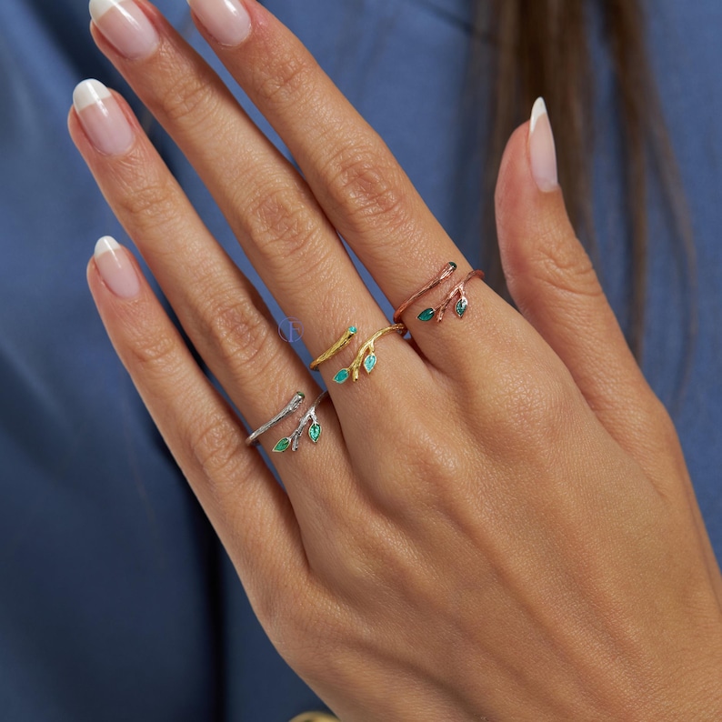 May include: Three gold, silver, and rose gold rings with a twig design and green enamel leaves. The rings are adjustable and can be worn on any finger.
