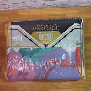 May include: A packaged double sheet set with a colorful floral pattern. The packaging reads "PERFECTION PERCALE" with a thread count of 180. The set includes four pieces and is labeled "NO IRON". The sheets feature a design with purple, teal, and red hues.