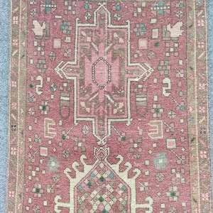 May include: A vintage pink and cream rug with a traditional Persian design. The rug has a central medallion and a border of geometric patterns.
