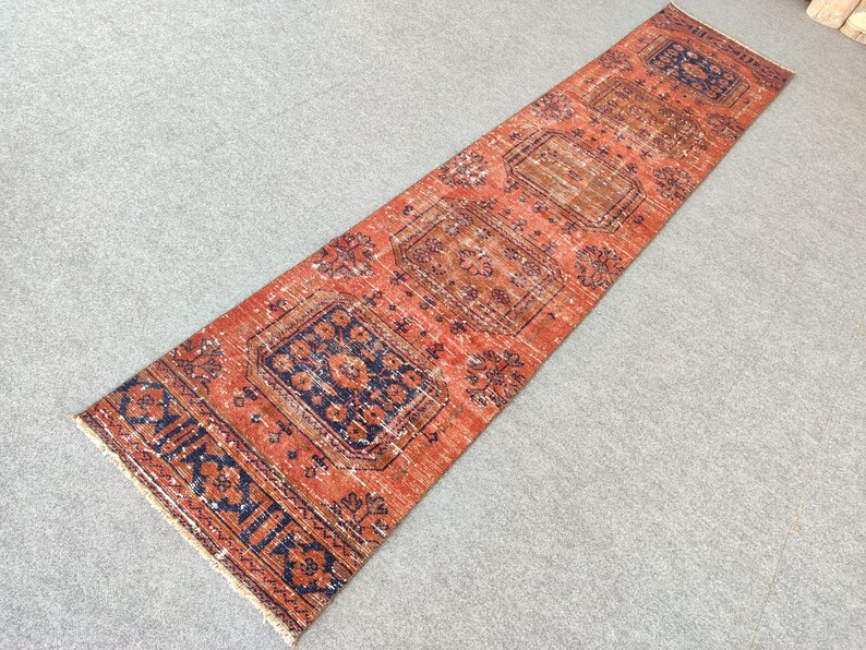 K&ouml;nnte beinhalten: Ein langer, rechteckiger Teppich mit traditionellem persischem Design. Der Teppich ist rot mit blauen und wei&szlig;en Akzenten. Der Teppich hat ein Blumenmuster und einen geometrischen Rand.