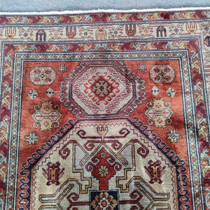 May include: A traditional rug with a red, beige, and blue geometric pattern. The rug has a fringe border and a central medallion.
