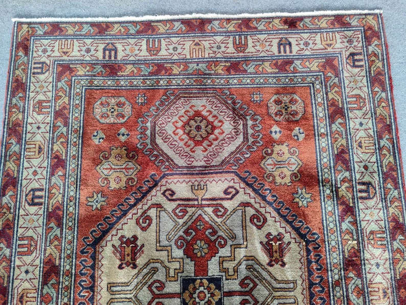 May include: A traditional rug with a red, beige, and blue geometric pattern. The rug has a fringe border and a central medallion.