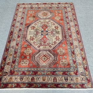May include: A traditional rug with a red, orange, and blue geometric pattern. The rug has a central medallion with a repeating pattern of stylized flowers and leaves.