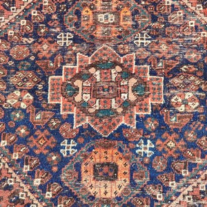 May include: A vintage Persian rug with a detailed geometric pattern in shades of red, blue, and brown. The rug features a central medallion with intricate floral designs.