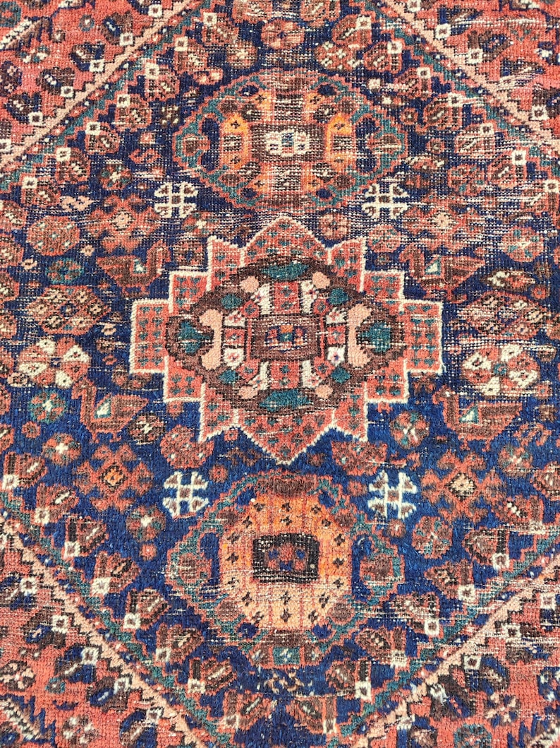 May include: A vintage Persian rug with a detailed geometric pattern in shades of red, blue, and brown. The rug features a central medallion with intricate floral designs.