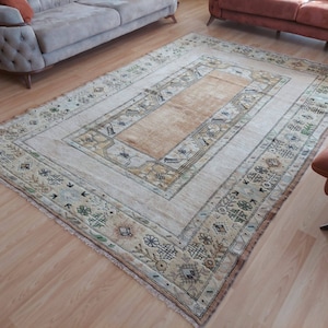Puede incluir: Una alfombra vintage con fondo crema y centro beige. La alfombra tiene un patr&oacute;n geom&eacute;trico con detalles en verde, marr&oacute;n y negro.