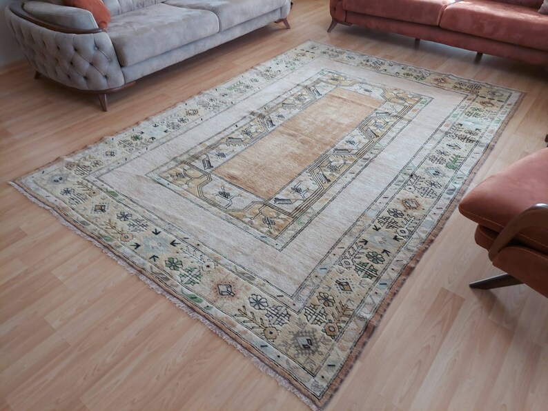 Puede incluir: Una alfombra vintage con fondo crema y centro beige. La alfombra tiene un patr&oacute;n geom&eacute;trico con detalles en verde, marr&oacute;n y negro.