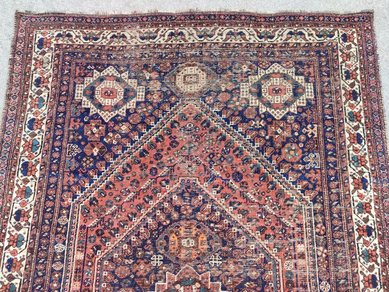 May include: A vintage Persian rug featuring a red, blue and cream colour scheme. The rug has a central medallion and intricate geometric patterns.