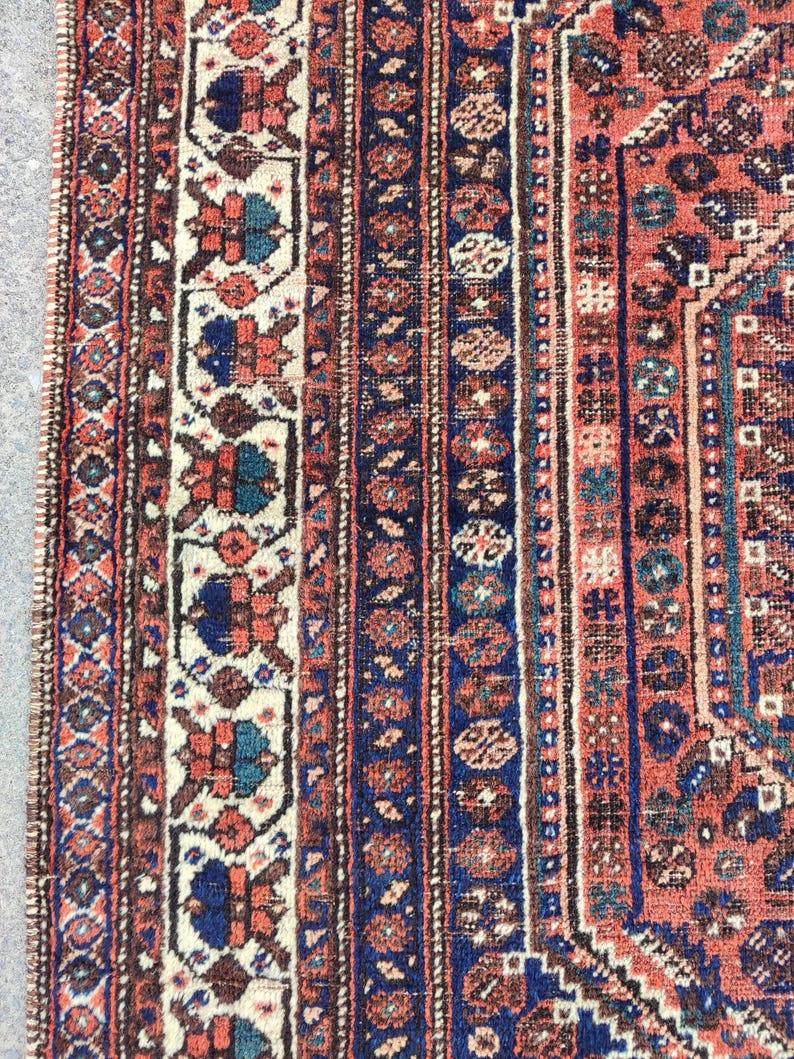 May include: Close-up of a red, blue and white patterned rug with intricate details. The rug has a traditional design with a central medallion and a border.