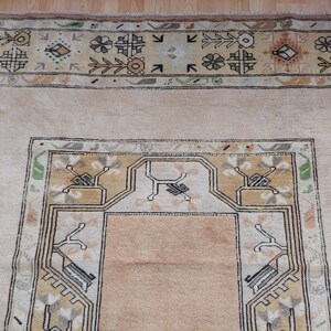 Puede incluir: Una alfombra beige con un patr&oacute;n geom&eacute;trico en tonos marrones, verdes y blancos. La alfombra tiene un medall&oacute;n central con un dise&ntilde;o geom&eacute;trico.