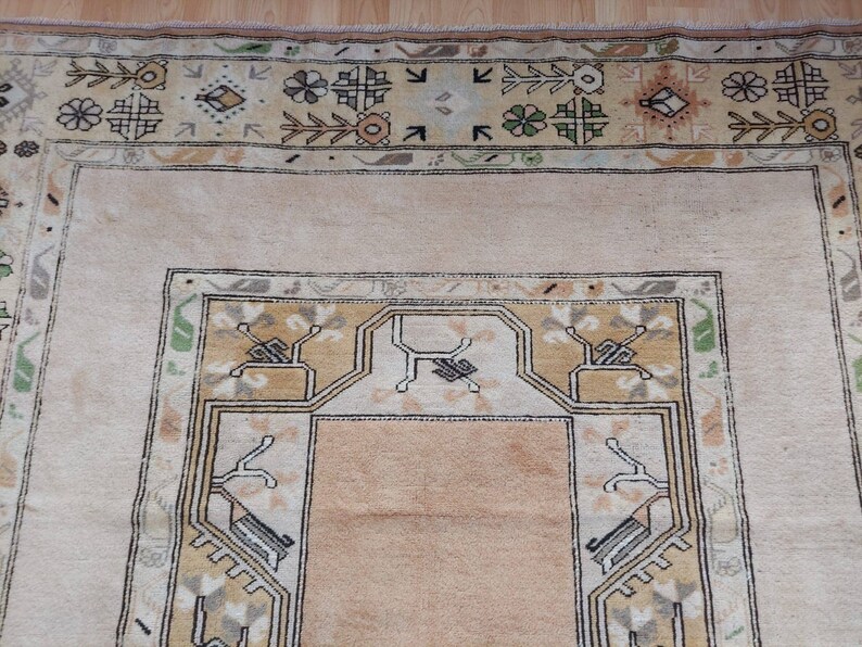 Puede incluir: Una alfombra beige con un patr&oacute;n geom&eacute;trico en tonos marrones, verdes y blancos. La alfombra tiene un medall&oacute;n central con un dise&ntilde;o geom&eacute;trico.