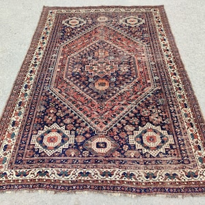 May include: A vintage Persian rug with a navy blue background and intricate red, white, and cream patterns. The rug has a diamond-shaped centre with a floral design and a border with a repeating geometric pattern.