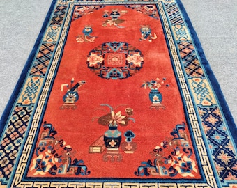 May include: A red rug with a blue and cream border. The rug features a central floral design with intricate details and several smaller floral motifs throughout. The rug has a traditional Chinese style.