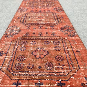 K&ouml;nnte beinhalten: Ein vintage roter und blauer L&auml;uferteppich mit geometrischem Muster. Der Teppich hat einen abgenutzten Look und ist aus Wolle.