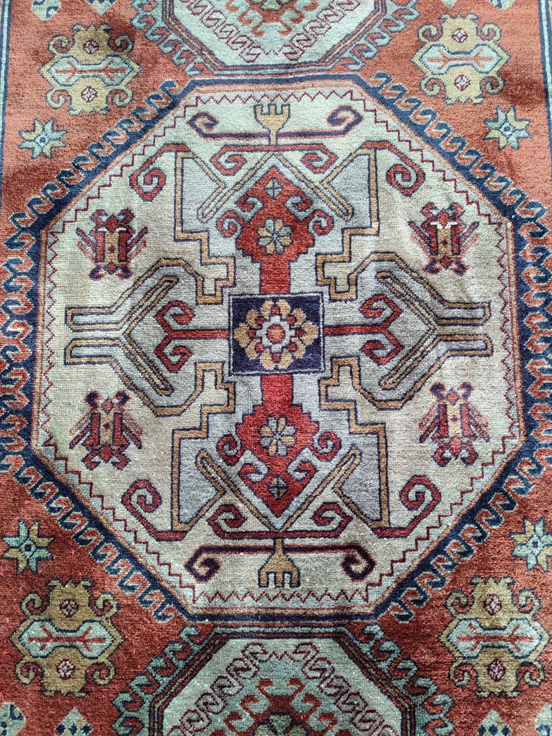 May include: A traditional rug with a geometric pattern in shades of red, blue, beige, and brown. The rug features a central medallion with intricate details and a repeating border.