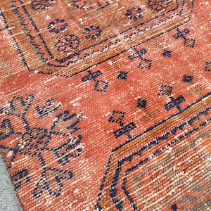 K&ouml;nnte beinhalten: Nahaufnahme eines roten und blauen Teppichs mit einem gemusterten Design, das einen verblassten, Vintage-Look hat. Der Teppich hat ein geometrisches Muster mit komplizierten Details.