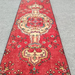 May include: A red runner rug with a traditional Persian design featuring intricate floral patterns in shades of cream, blue, and green.