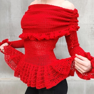 May include: Red off-the-shoulder knitted sweater with crocheted lace trim and bell sleeves.
