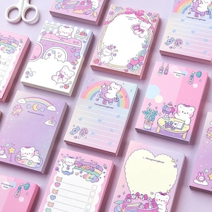 May include: A set of 10 pink and purple memo pads with cute bear illustrations and rainbow designs. The pads feature different designs, including a bear riding a unicorn, a bear with a lollipop, and a bear with a cake. The text "Mangmengbear" is printed on each pad.