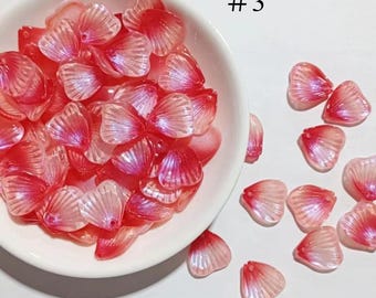 May include: A white bowl filled with iridescent pink and white heart-shaped beads.  The bowl is sitting on a white surface.  There are more beads scattered around the bowl.  #3