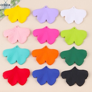 May include: A selection of ginkgo leaf pendants in a range of colours: yellow, purple, white, pink, fuchsia, green, teal, orange, dark green, red, blue, and black. Each pendant has a small hole for threading. Measurements are in centimetres.