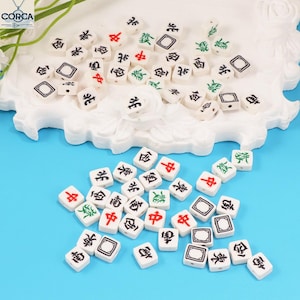 Peut inclure: Un ensemble de petits carreaux de Mahjong blancs avec des symboles et des caractères noirs, rouges et verts. Les carreaux sont dispersés sur une surface blanche décorative sur un fond bleu vif.