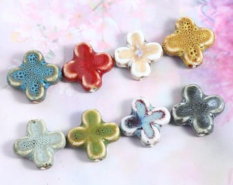 Può includere: Assortimento di otto perline in ceramica a forma di fiore in vari colori, tra cui blu, verde, rosso, giallo e bianco. Ogni perlina ha un motivo a fiore a quattro petali con una superficie testurizzata.