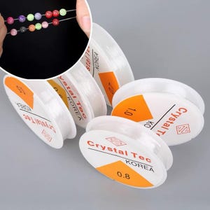 May include: Clear elastic beading cord spools with orange and white labels. The labels display the brand "Crystal Tec KOREA" and cord thickness in millimeters. A close-up shows colorful beads strung on the cord.