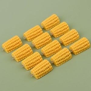 Pode incluir: Dez encantos de milho amarelo com argolas de salto prateadas. Os encantos são feitos de plástico e têm a forma de espiga de milho. São perfeitos para adicionar um toque de fantasia às suas joias ou artesanato.