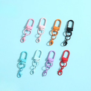 Pode incluir: Uma variedade de oito fechos giratórios de metal coloridos em vários tons, incluindo rosa, laranja, preto, azul-petróleo, azul claro, roxo e vermelho. Cada fecho apresenta um gancho de lagosta e vários anéis de conexão, ideal para chaveiros ou projetos de artesanato.