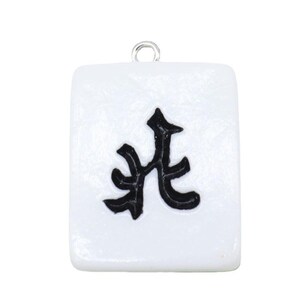 May include: A white rectangular charm with a black Chinese character. The charm has a silver loop at the top for attaching to a necklace or bracelet. The design is simple and clean, with a focus on the bold black symbol.