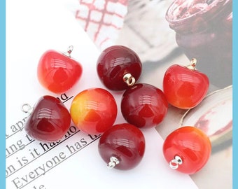 May include: Eight red and orange cherry-shaped charms with silver loops. The charms are made of plastic and are about 1 inch in diameter.