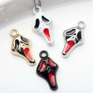May include: Four Scream mask pendants in gold, silver, black, and white. Each pendant features a red mouth and black eye details. The pendants are designed for jewelry making.