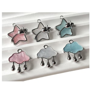 May include: Six silver charms with a white, pink or blue enamel finish. The charms are shaped like stars and clouds with raindrops.