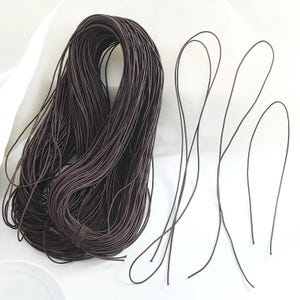 May include: A bundle of dark brown leather cord, tightly wound, with several strands separated. The cord appears smooth and flexible, suitable for various crafting projects. The color is a deep, rich brown.