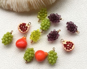 Può includere: Assortimento di ciondoli a forma di frutta, tra cui uva, melograni e una pera. I ciondoli sono in vetro e hanno un aspetto realistico. Sono perfetti per aggiungere un tocco di fantasia a gioielli o artigianato.