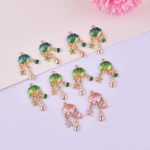 May include: A collection of gold-toned seashell charms with colorful enamel details. Each charm features a shell shape in shades of green, blue, and coral, with dangling starfish, teardrops, and gemstones. Ideal for jewelry making.