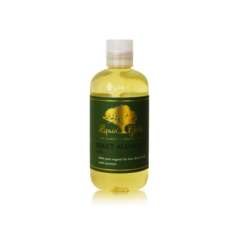 Puede incluir: Una botella de vidrio transparente con una etiqueta dorada que dice "Liquid Gold The Academy of Organic Oils Sweet Almond Oil 100% pure organic for hair skin & body multi purpose". La botella est&aacute; llena de un l&iacute;quido amarillo claro.