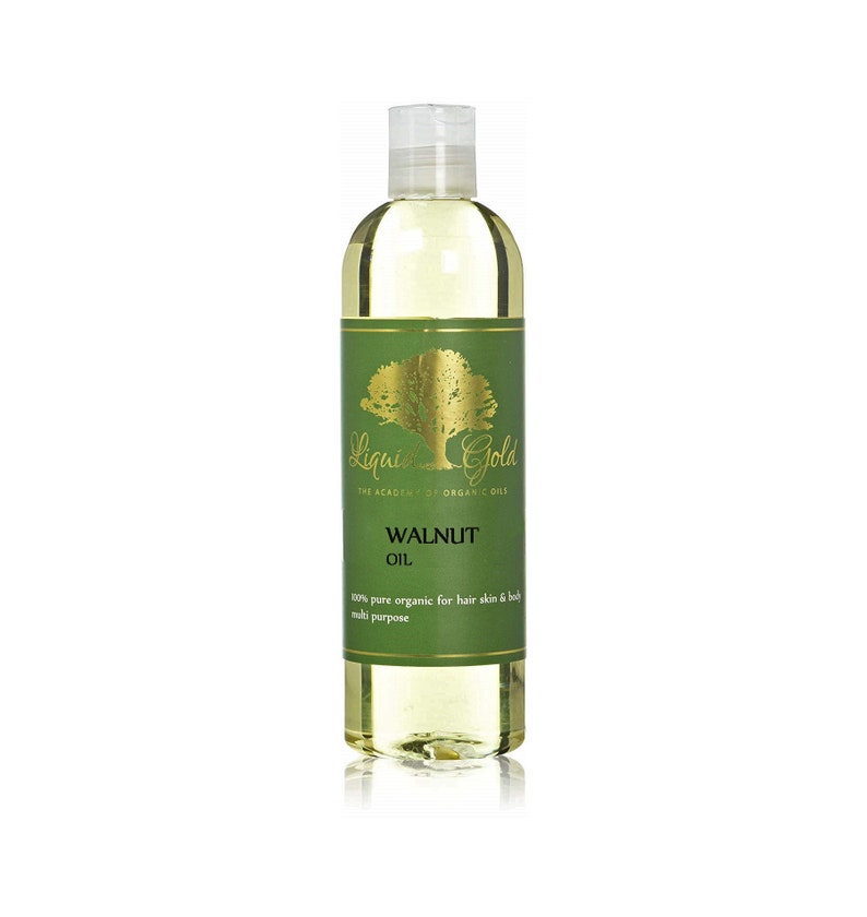 Pode incluir: Uma garrafa de vidro transparente de &Oacute;leo de Noz Liquid Gold. A garrafa tem um r&oacute;tulo dourado com uma &aacute;rvore verde e o texto "Liquid Gold The Academy of Organic Oils Walnut Oil 100% pure organic for hair skin & body multi purpose".