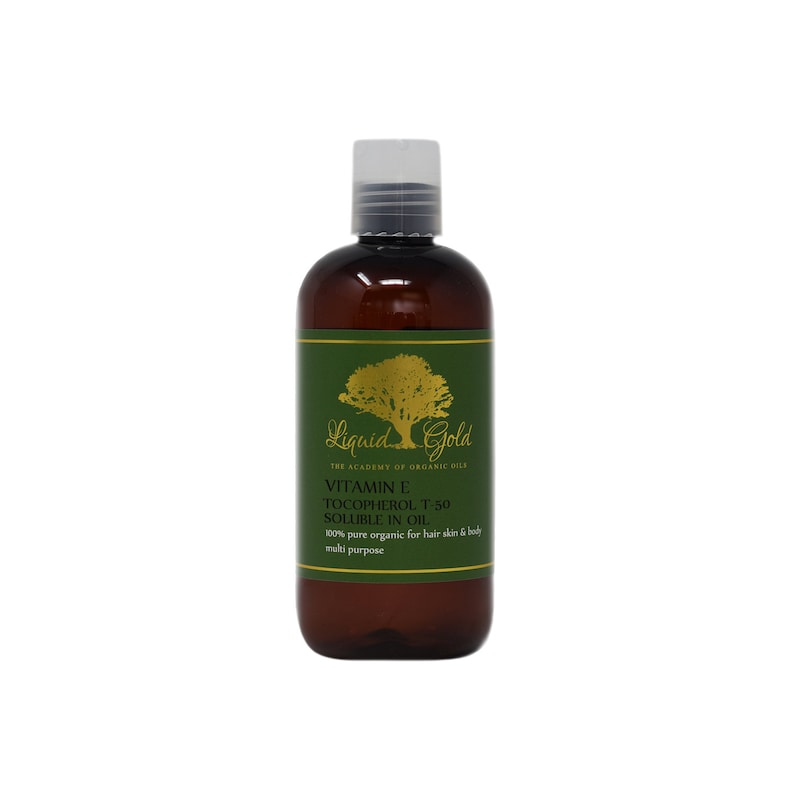 May include: A brown bottle of Liquid Gold Vitamin E Tocopherol T-50 Soluble in Oil. The bottle has a green label with a gold tree and the text "Liquid Gold" and "The Academy of Organic Oils".