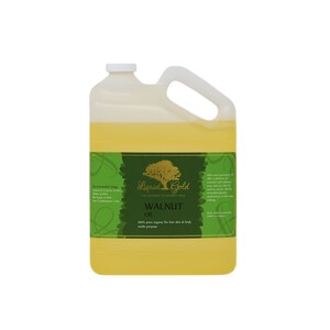Pode incluir: Um gal&atilde;o de &oacute;leo de noz de Liquid Gold. O r&oacute;tulo &eacute; verde com uma &aacute;rvore dourada e o texto "Liquid Gold The Academy of Organic Oils &Oacute;leo de noz 100% puro org&acirc;nico para cabelo, pele e corpo multiusos".